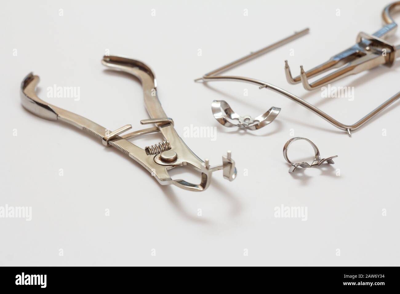 Metal instrument for dental treatment. Dental tongs, clasps and cofferdam frame on white background. Medical tools. Shallow depth of field. Stock Photo