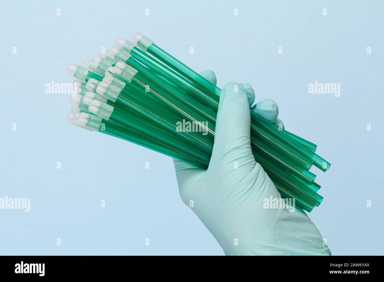 Dentist's hand in a latex glove with saliva ejectors on blue background. Medical tools concept. Stock Photo