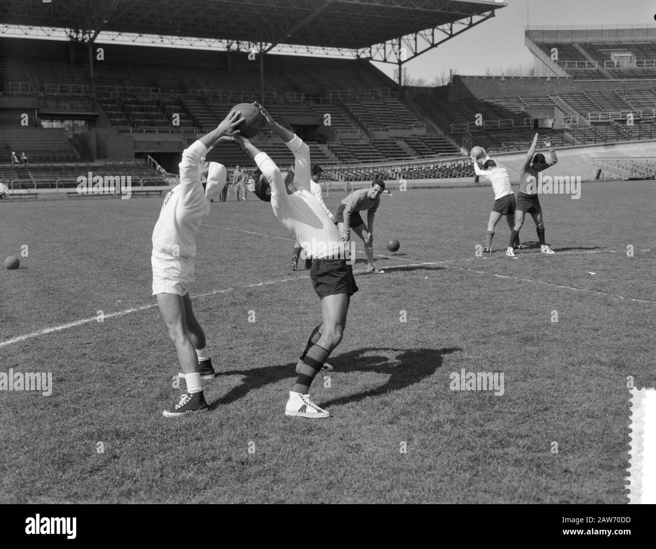 Training of Mexican soccer in the Olympic Stadium  [Mexican soccer players give each other back to back a ball] Date: April 18, 1961 Location: Amsterdam Keywords: sports stadiums, football, soccer , football Stock Photo