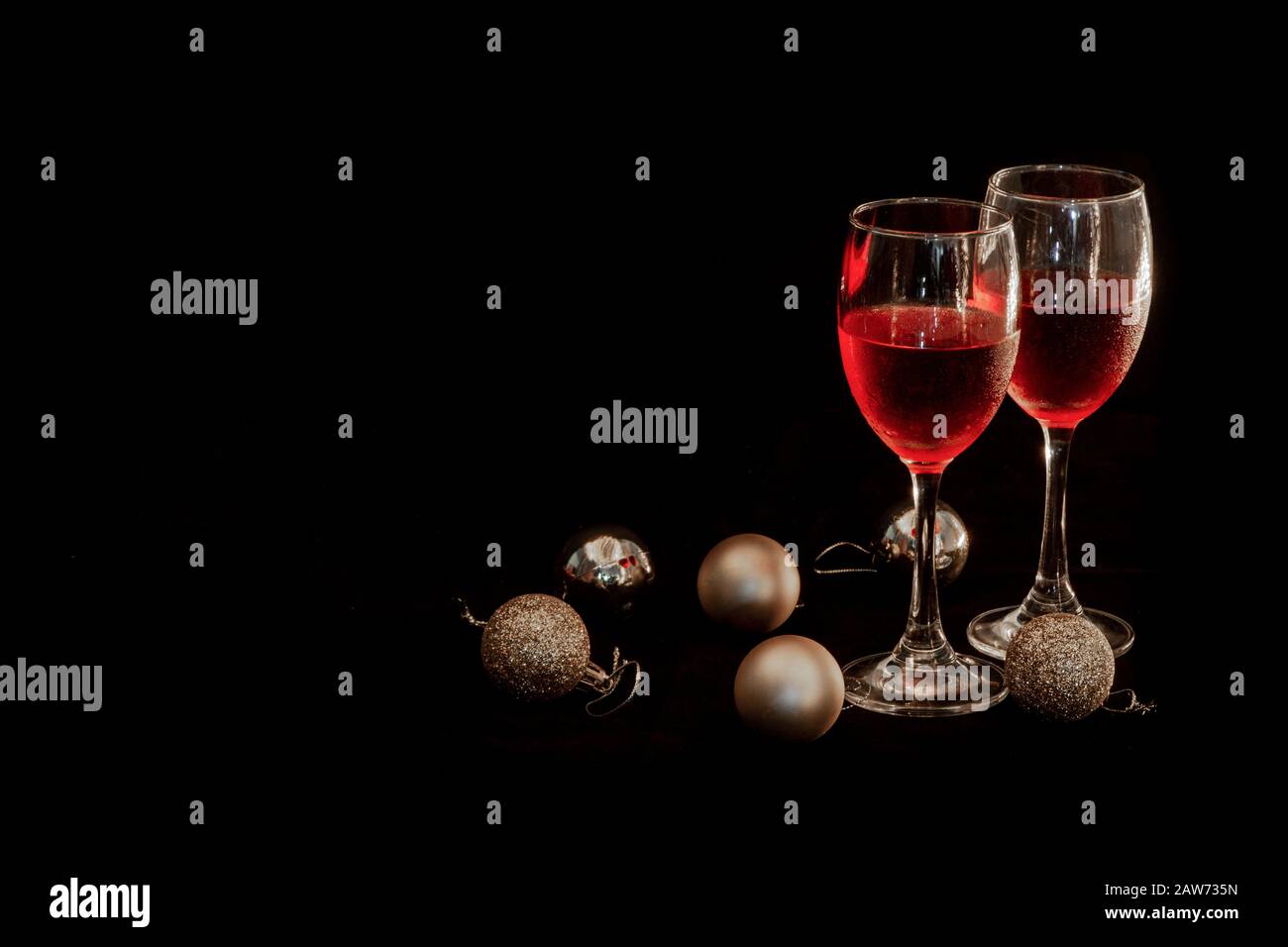 Celebration theme with  two red wine glass and Golden round ball on  black background Stock Photo