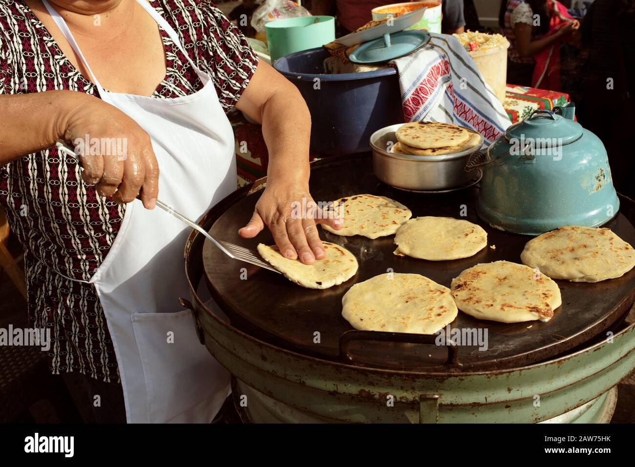 Native woman cooking traditional pupusas (cheese stuffed thick flatbread). Street food in Antigua, Guatemala. Jan 2019 Stock Photo
