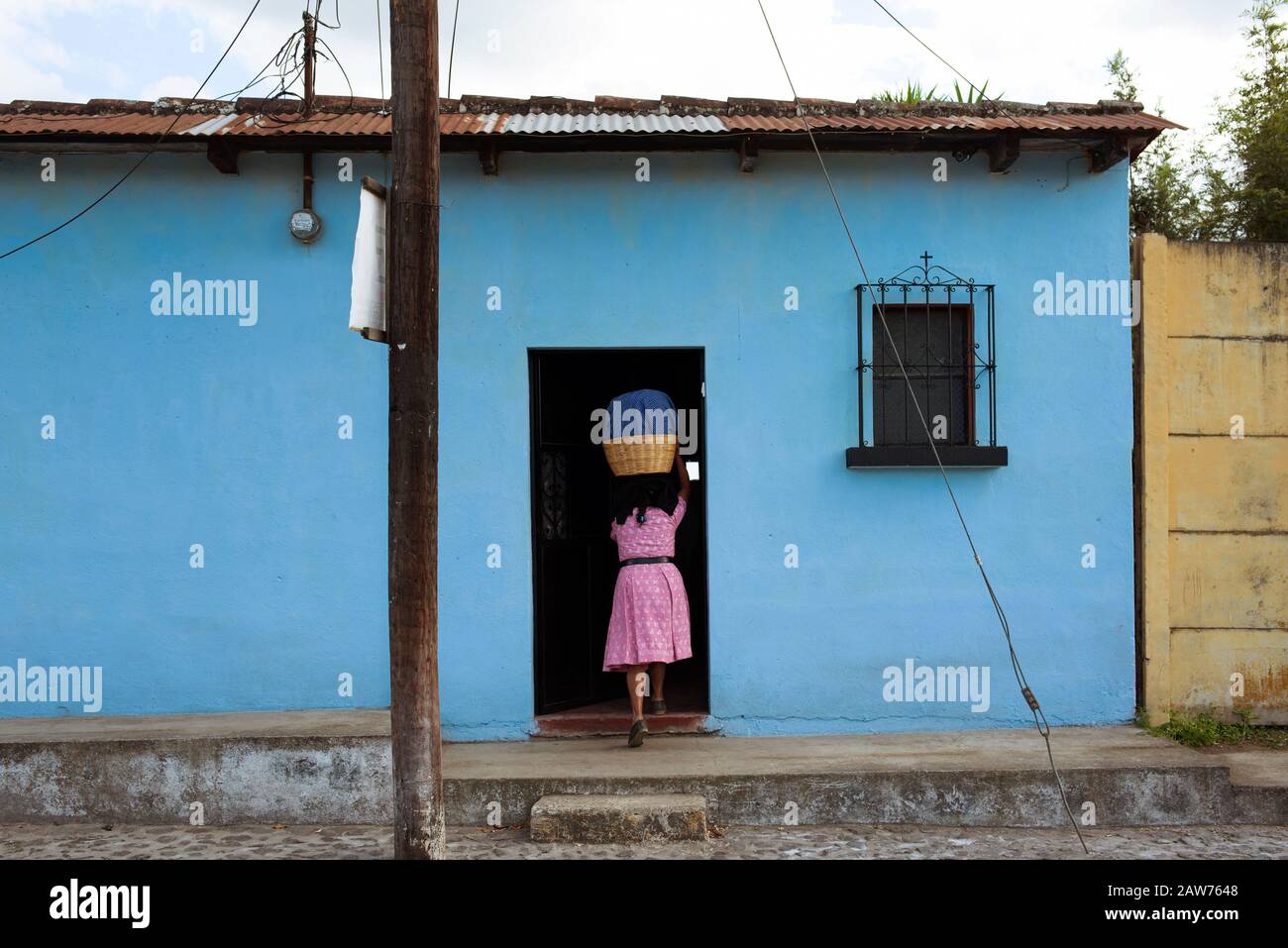 Latina woman doing household chores, head-carrying basket. Everyday living in Antigua, Guatemala Stock Photo