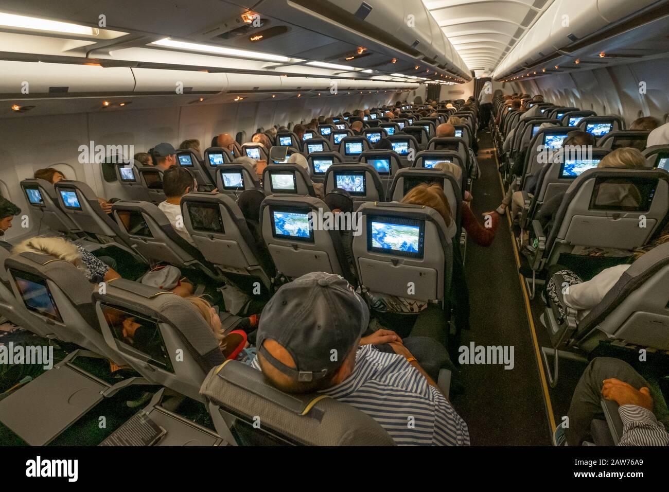 People are entertained with movies during the flight to their resort. Stock Photo