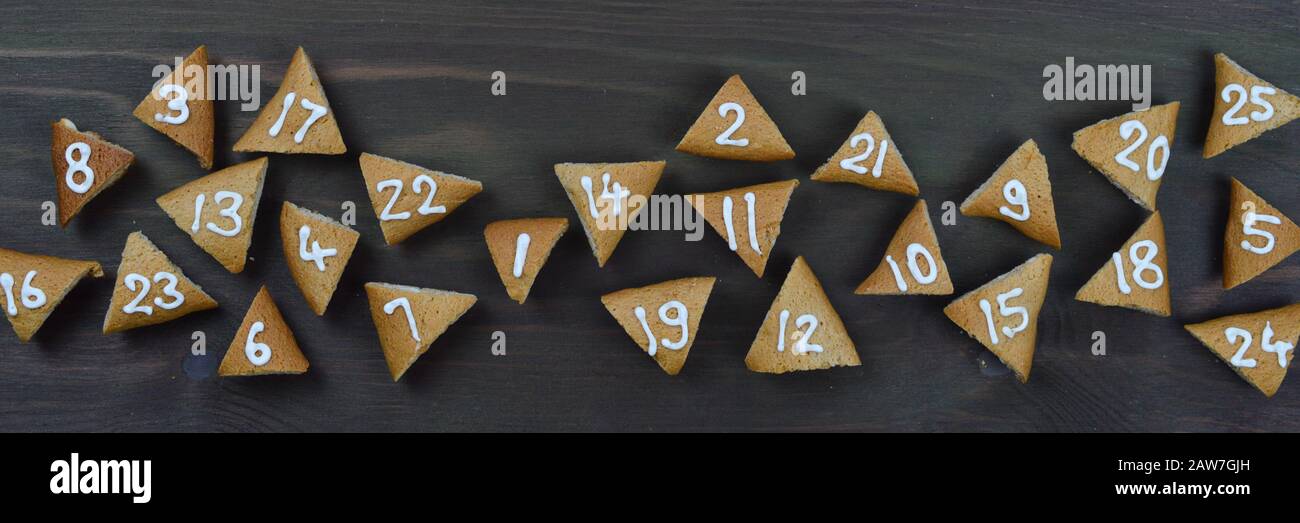 ribbon of twenty five numbered advent cookies on brown wooden background Stock Photo