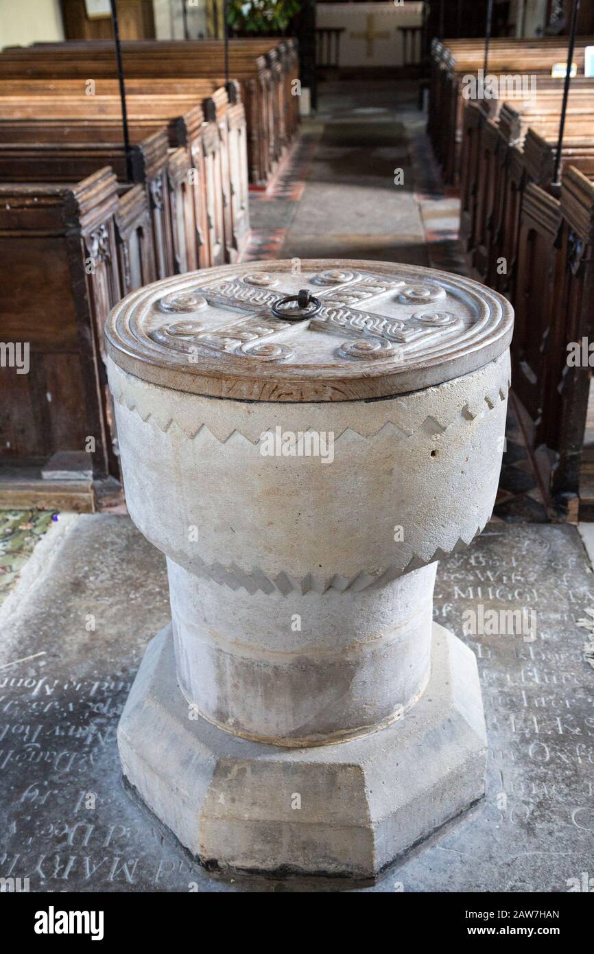 Simply decorated stone 12th century baptismal font inside church at Stanton St Bernard, Wiltshire, England, UK Stock Photo