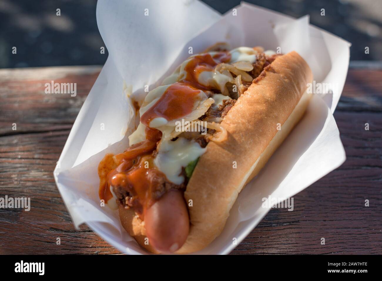 Close up of hot dog with ketchup and onion. Sausage in bread bun with onion and tomato sauce. Outdoor fast food background Stock Photo