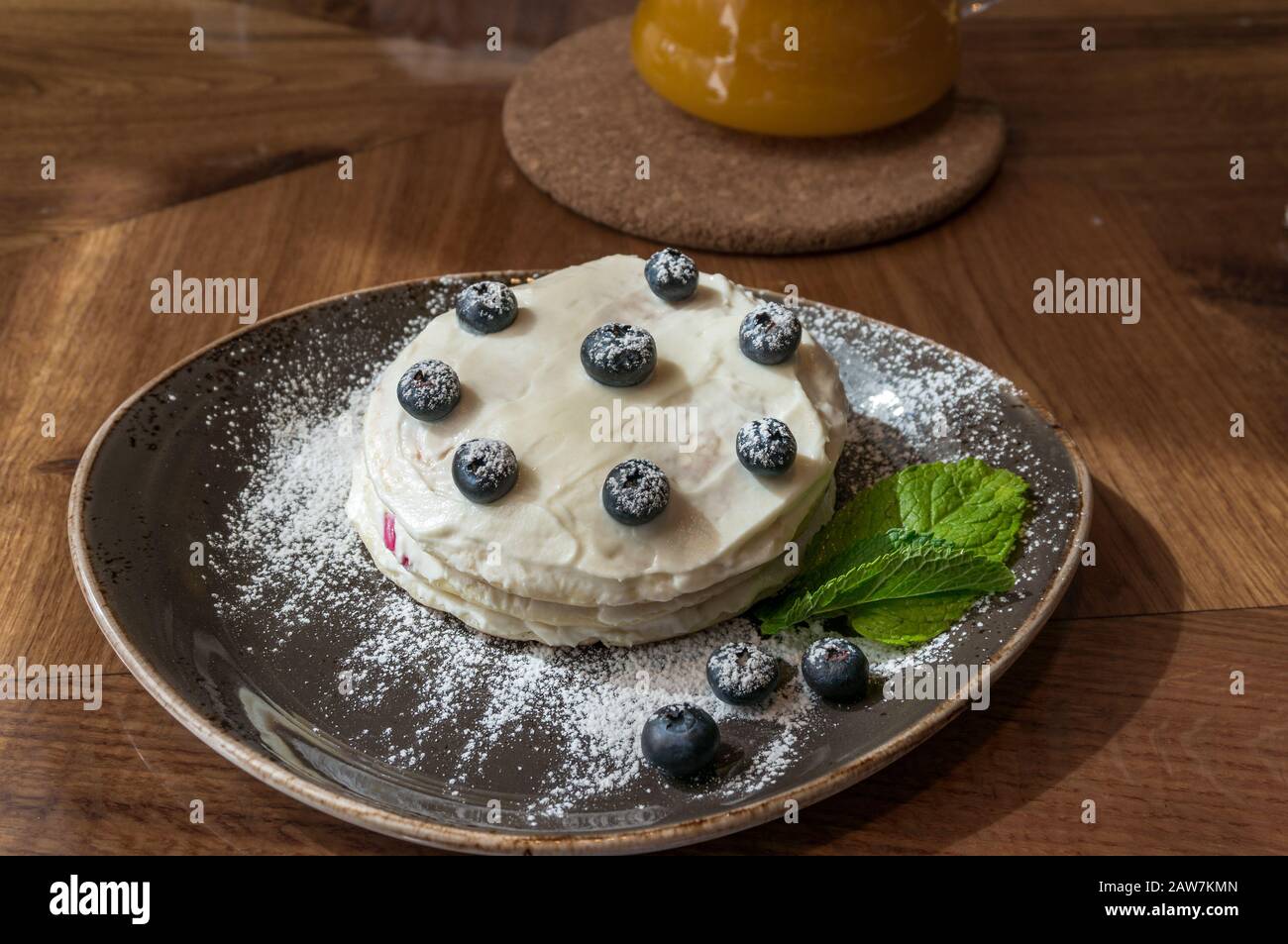 Layered cake with fresh blueberries and green mint leaves on rustic plate Stock Photo