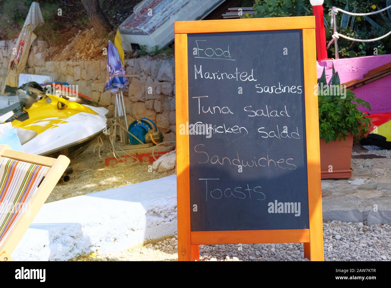 Black board menu black color with an inscription - marinated sardines, tuna salad, chicken salad, sandwiches, toasts. Chalkboard is standing near the Stock Photo