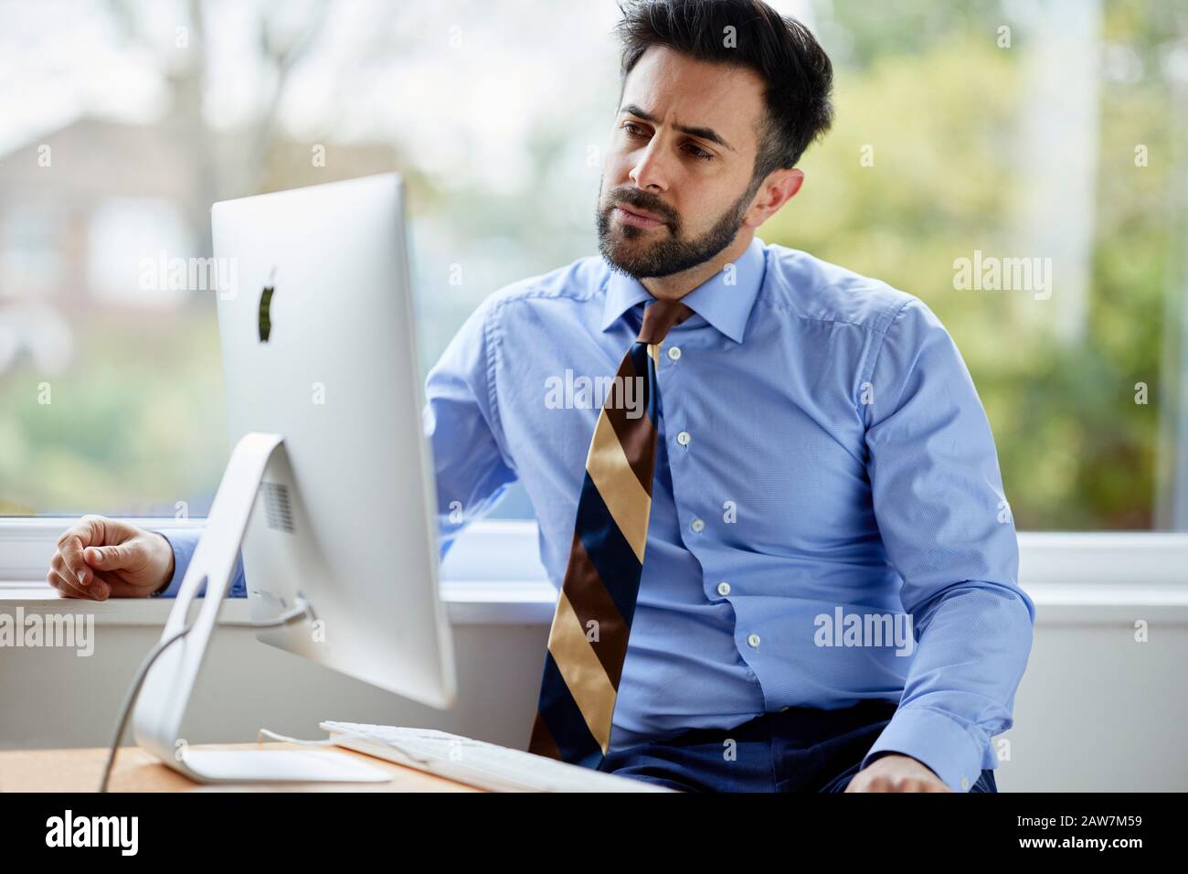 Man sat at computer thoughtful Stock Photo