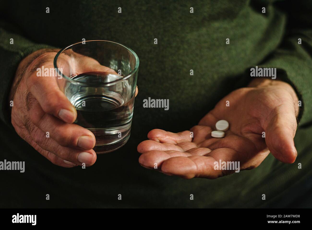 Elderly man taking his medication, two tablets. Stock Photo