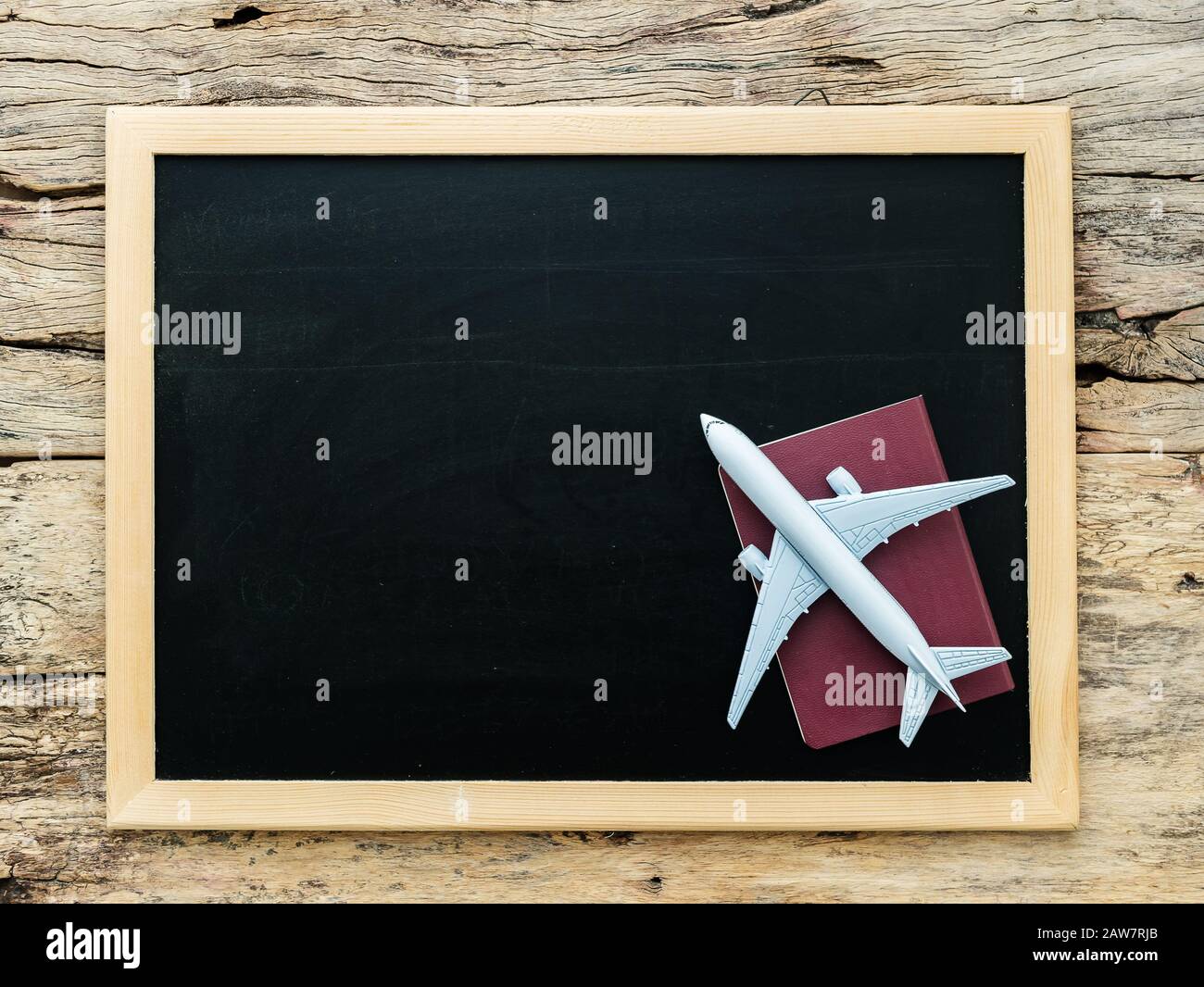 white plane model on red cover passport over blank empty black chalkboard for copy space on wooden background. travel by flight concept Stock Photo