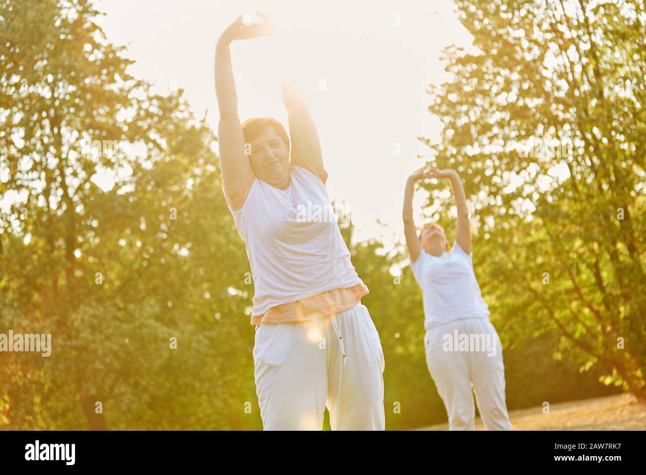 Two female seniors do an exercise for relaxation in the park Stock Photo