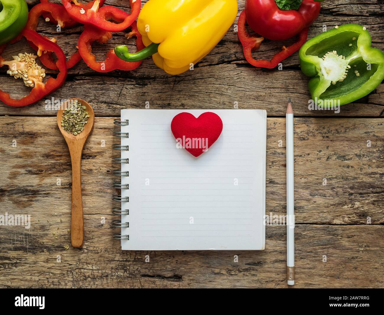 flat lay of blank recipe cooking book and utensils with herbs and colorful bell pepper over wooden background. top view with copy space. food recipe a Stock Photo