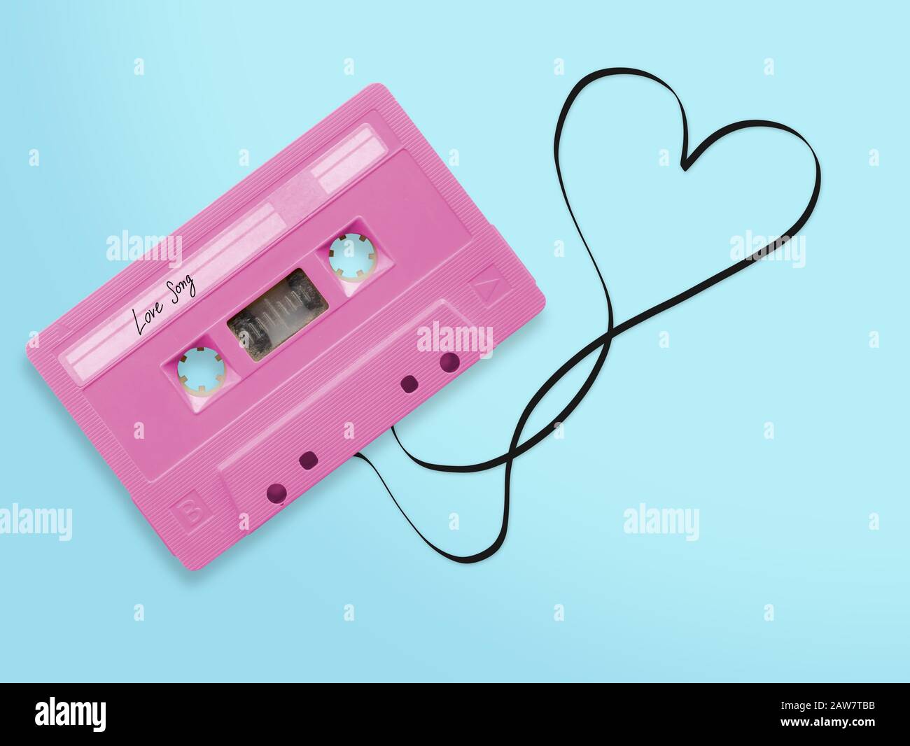 pink audio cassette tape with label tag love song tangled tape ribbon heart shape isolated on blue background, top view. Stock Photo