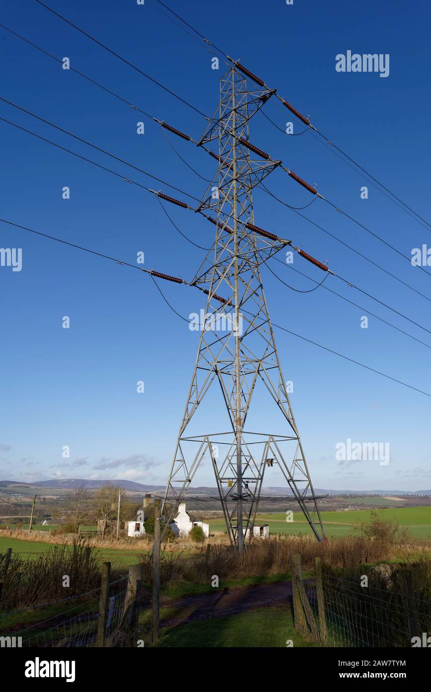 Close Up of an Electricity Pylon in a Field within the small village of Aberlemno, with derelict Farm Cottages in the background. Stock Photo