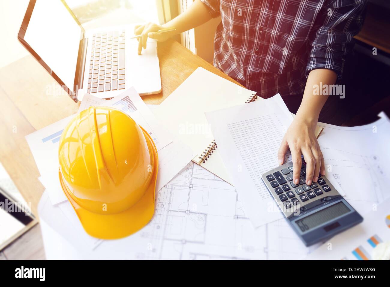 Asian engineer , architect woman using calculator for accounting and analyzing building structure from blueprint and paper chart in front of computer Stock Photo