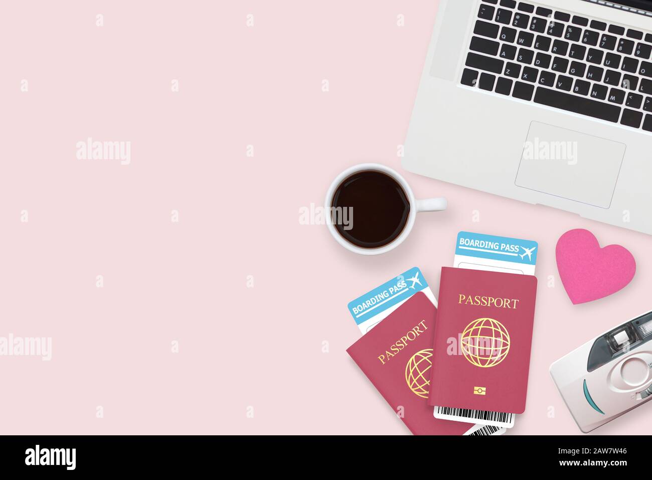 flat lay of red heart on two passport , coffee , computer laptop and copy space on pink pastel background. travel , honeymoon and vacation concept Stock Photo