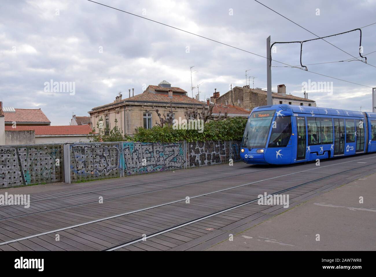 A Montpellier tram on the elevated section of the network alongside traditional housing near the city centre, Montpellier, France Stock Photo
