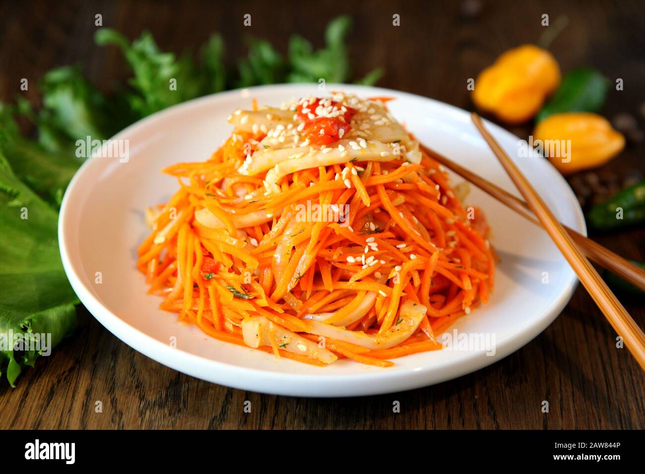 Carrot Korean squid meat salad in a plate with chopsticks on wooden oak