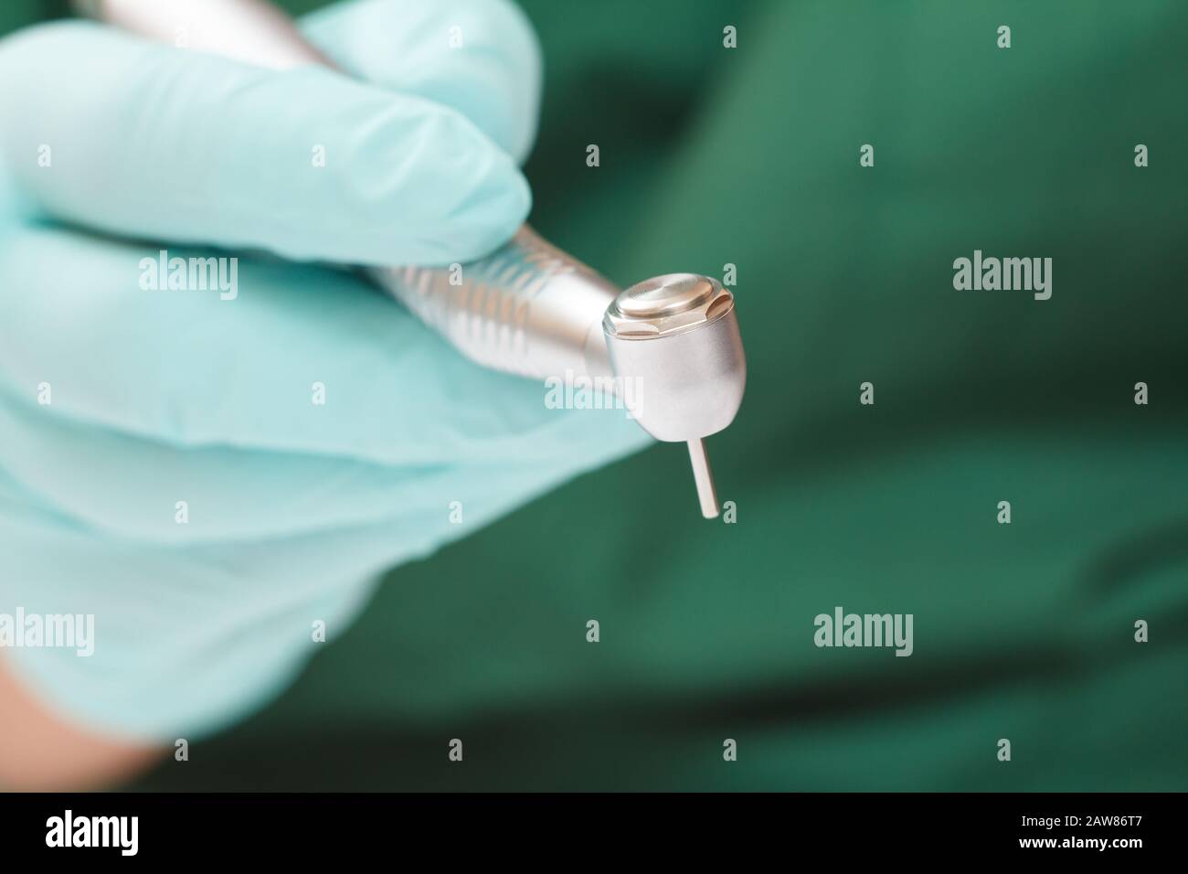 Close-up dentist's hand in a latex glove with high-speed dental handpiece on blurred background. Medical tools concept. Shallow depth of fiel. Stock Photo