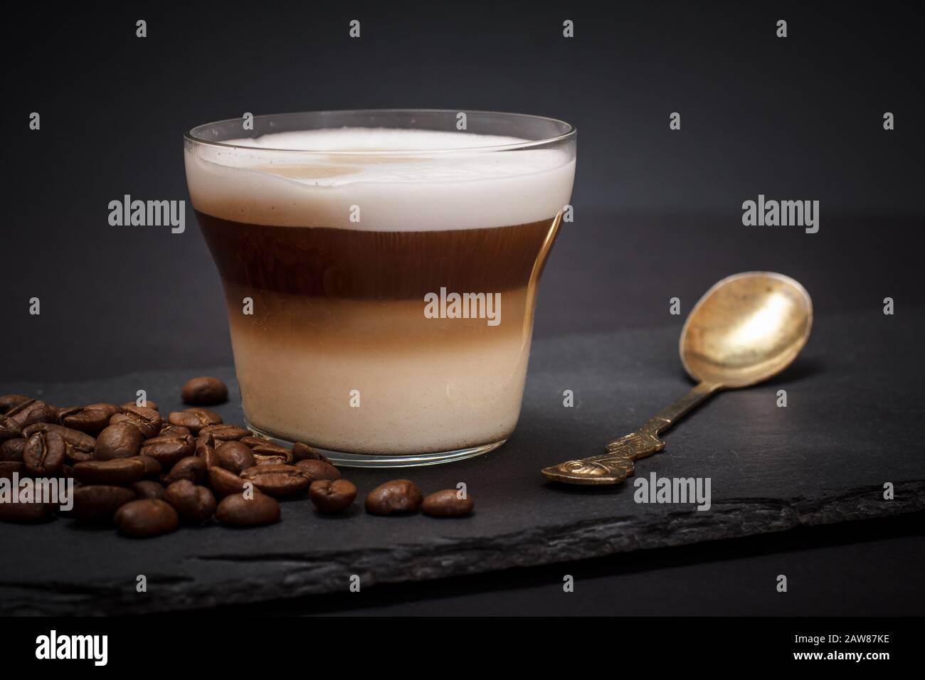 Cup of cappuccino, coffee beans and spoon on black background. Stock Photo