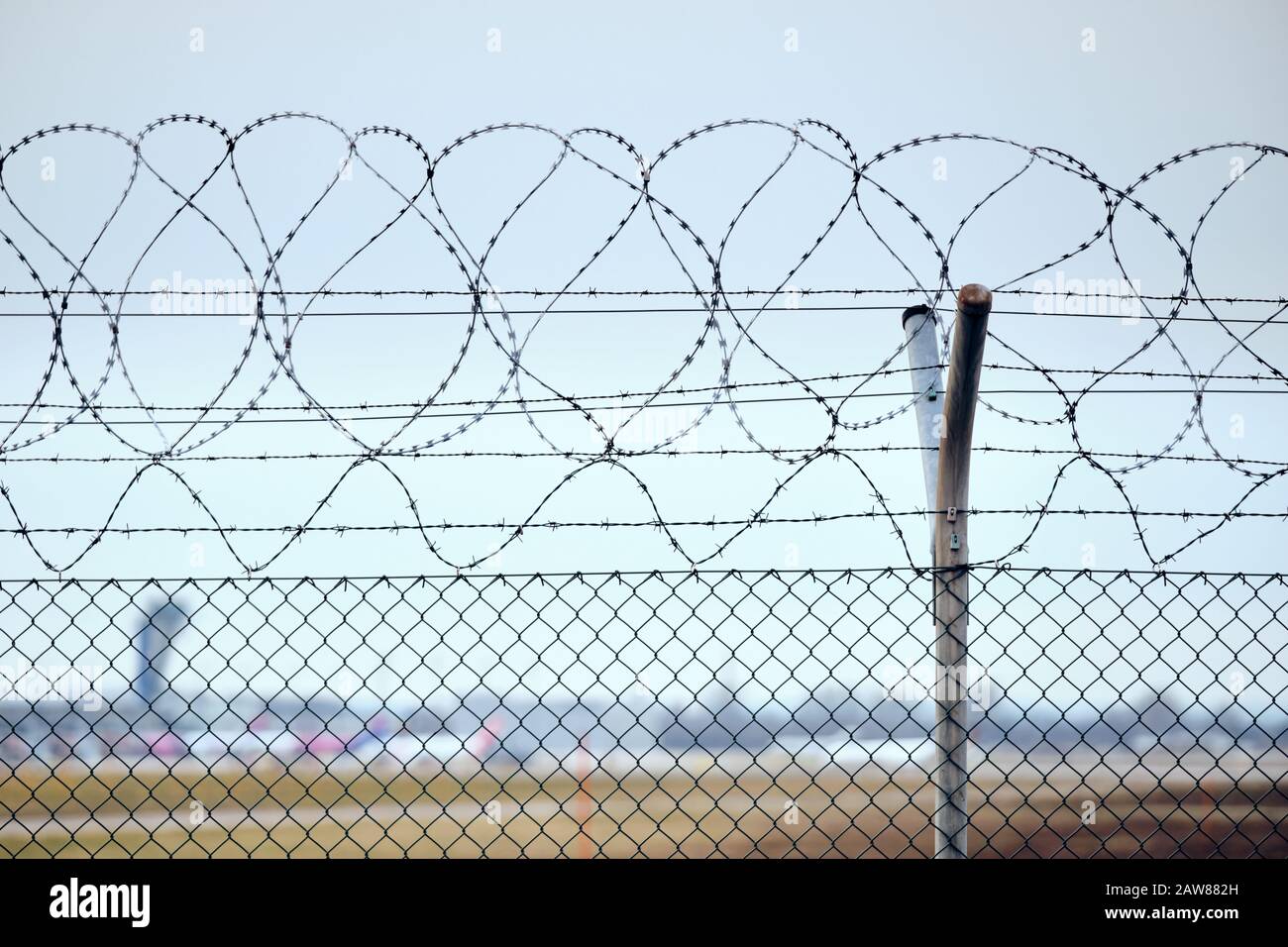 High chain-link fence with razor-barbed wire at the top protecting an airport. Stock Photo