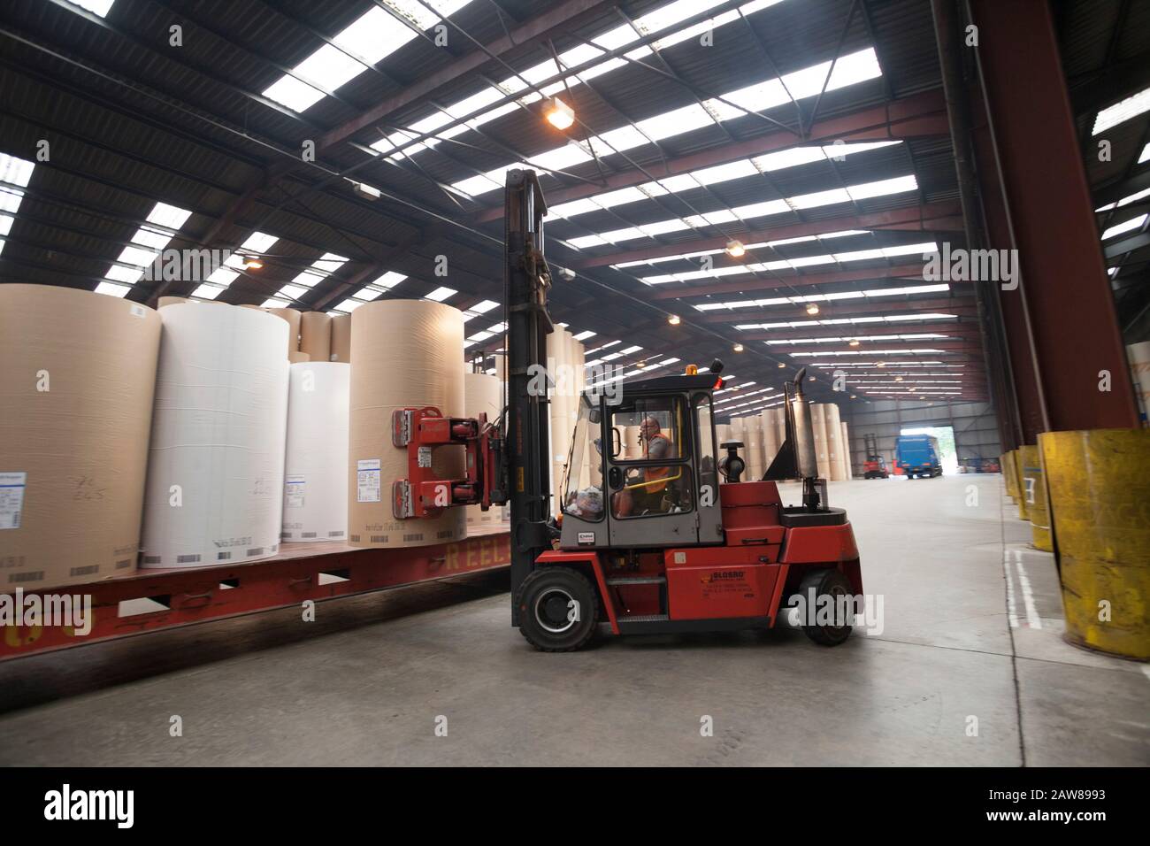 red forklift lifting a new paper roll in a paper warehouse Stock Photo