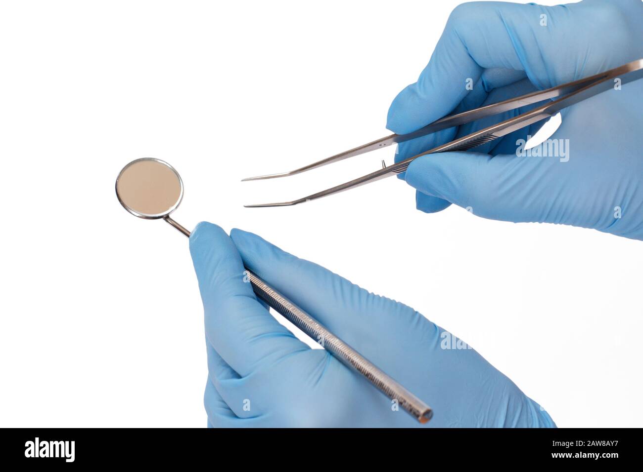 Dentist's hands in blue latex gloves with tweezers and mouth mirror on white isolated background. Medical tools concept. Stock Photo
