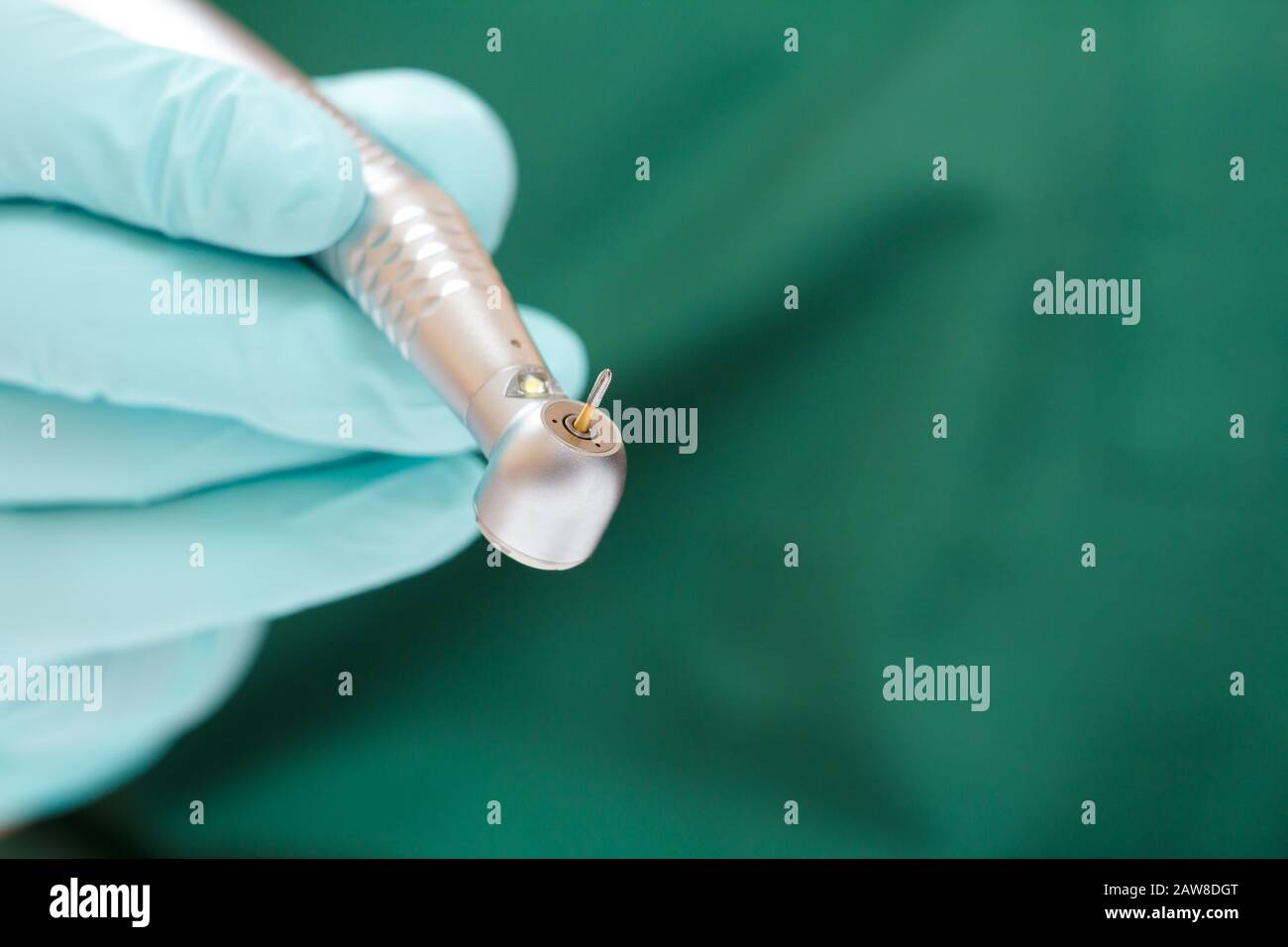 Dentist's hand in a latex glove with new high-speed dental handpiece on blurred background. Medical tools concept. Stock Photo