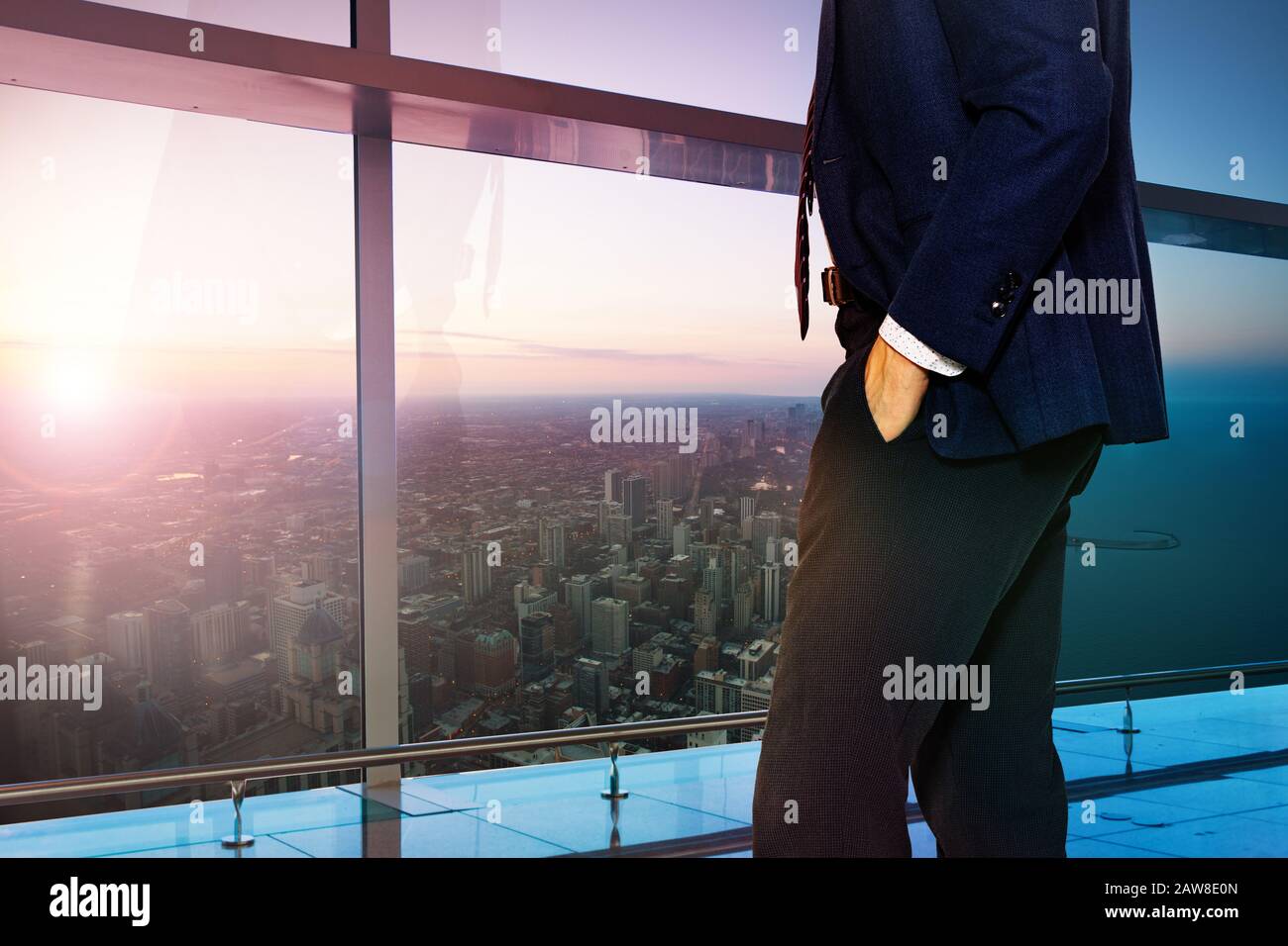 Back of businessman in suit standing near sunset window of downtown ...