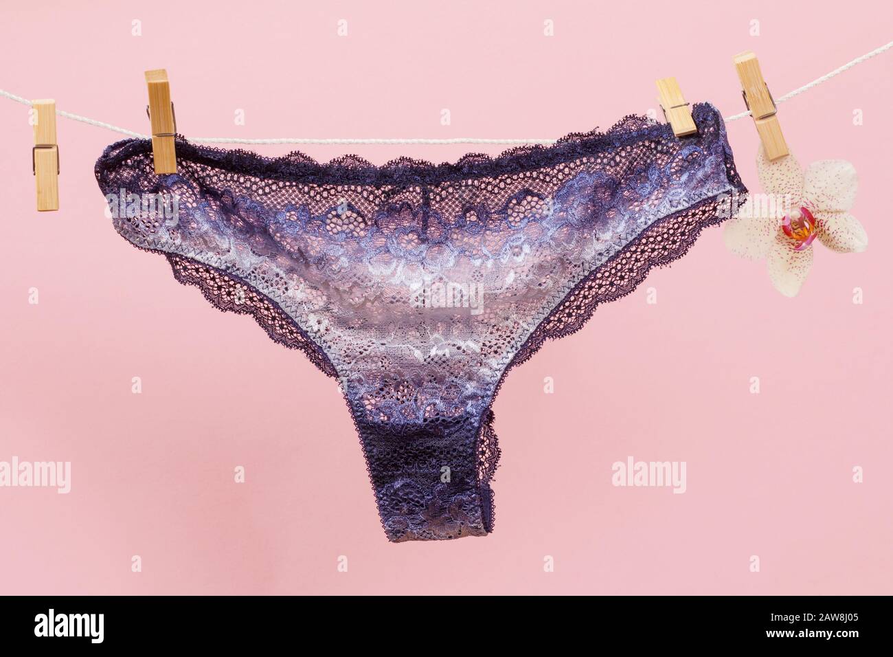New purple panties on clothesline with clothespins in pink background. Woman underwear. Top view. Stock Photo