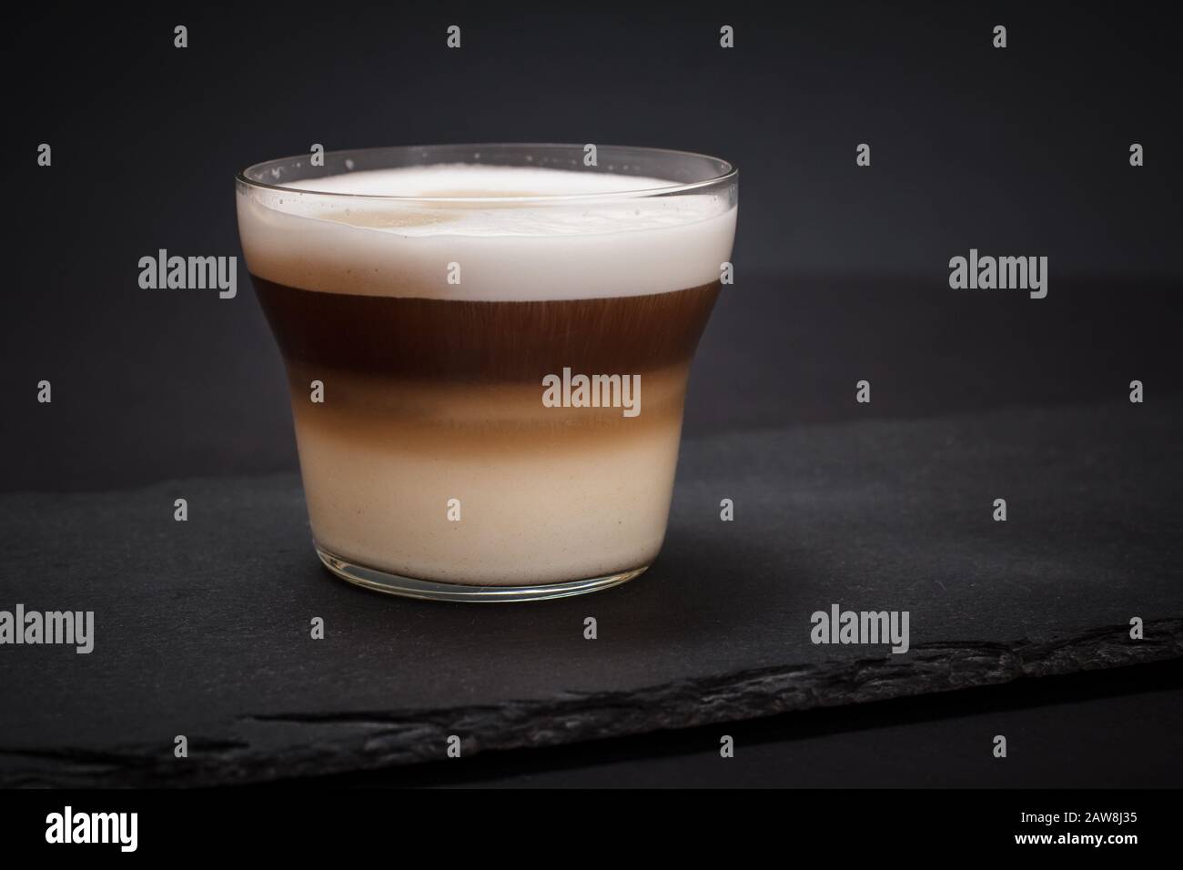 Cup of cappuccino on black stone board and dark background. Stock Photo