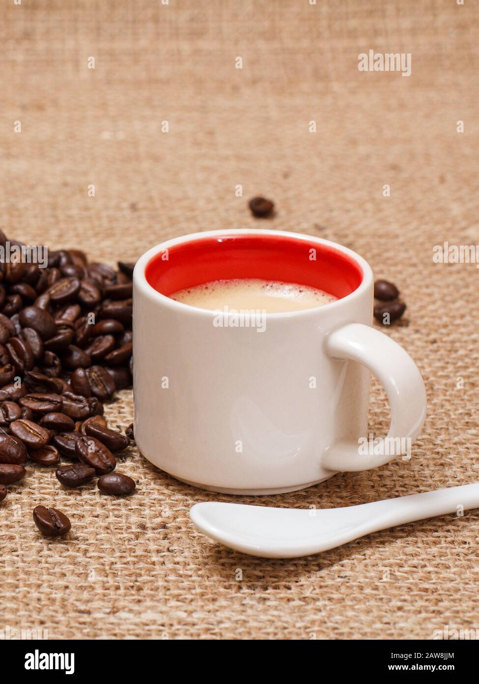 Cup of coffee, spoon and roasted coffee beans on sackcloth. Stock Photo