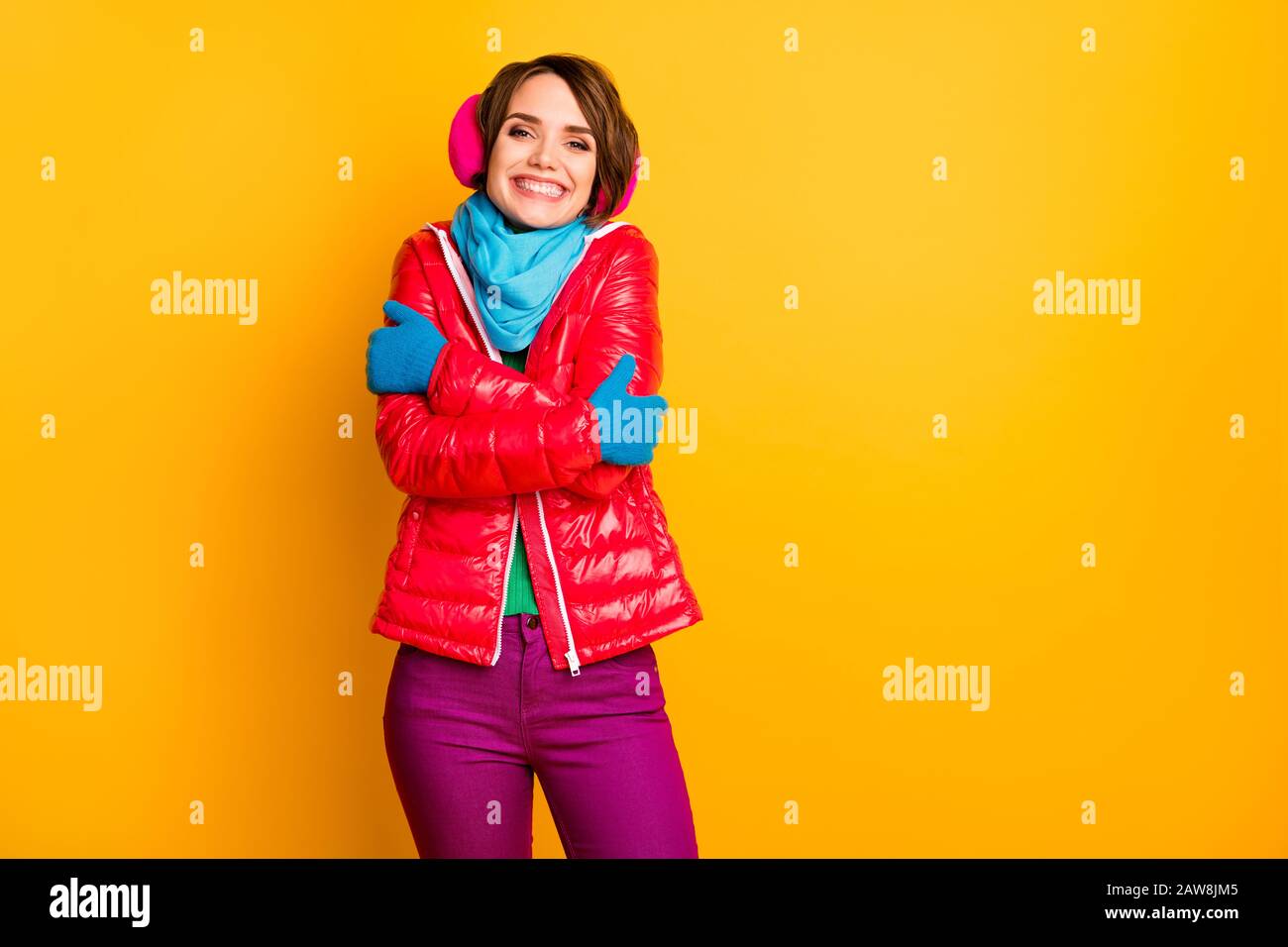Photo of funny cheerful lady enjoy warm coat in frosty weather hug herself wear casual short red overcoat blue scarf gloves earmuffs pants isolated Stock Photo
