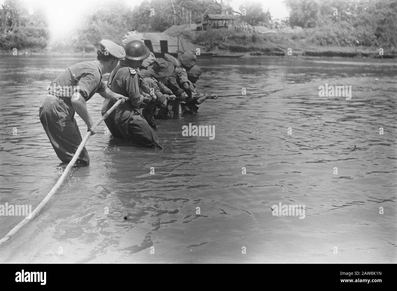 [Exercise? A row of soldiers standing in a river and pulling a long rope] Date: October 1948 Location: Indonesia Dutch East Indies Stock Photo