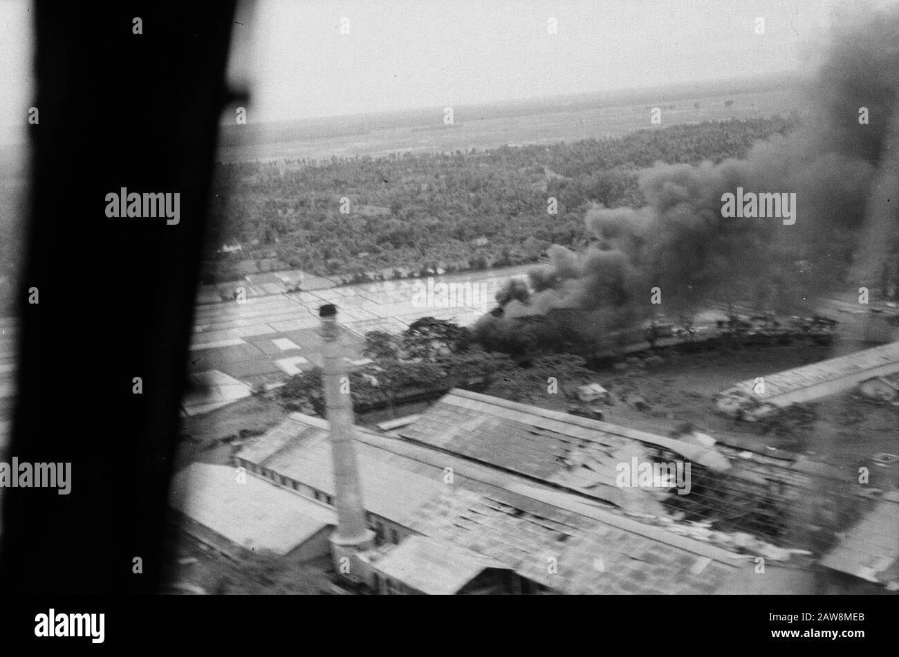 Food et al dropping infantry [2nd Police Action in December 1948]  [Luchtopname. Factory Complex with rice fields. Visible are vandalism. A building is on fire] Date: December 1948 Location: Indonesia Dutch East Indies Stock Photo