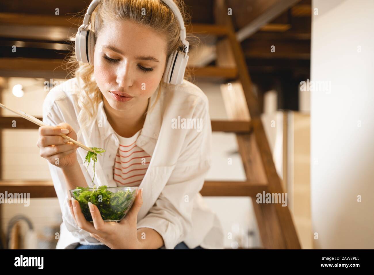 Attentive young woman looking into bowl with algae Stock Photo