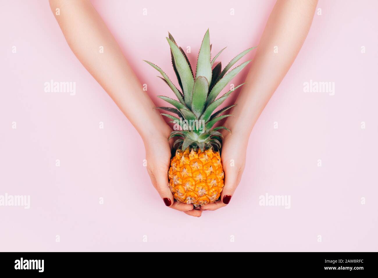 Hands with pineapple on stylish pink background. Stock Photo