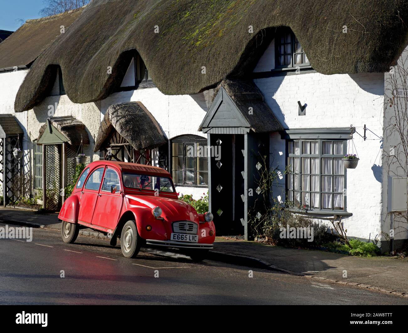 Citroen 2CV parked outside thatched cottage in Dunchurch, Warwickshire, England UK Stock Photo