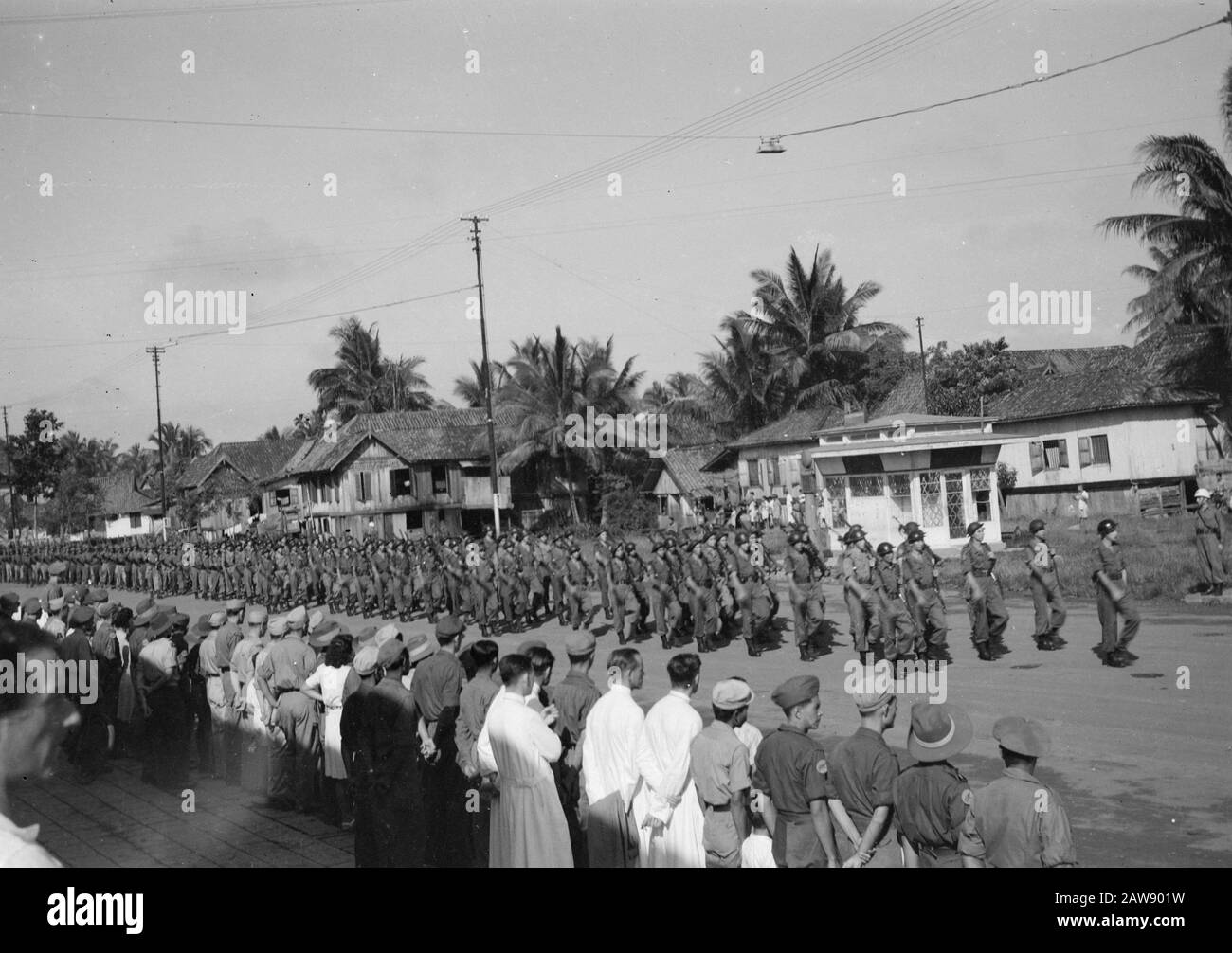 [Military parade in the village. Many people in military uniform watch] Annotation: In some men along the way, the sleeve logo KNIL brigade Bali-Lombok, battalion Gajah Merah visible Date: 01/01/1947 Location: Indonesia Dutch East Indies Stock Photo