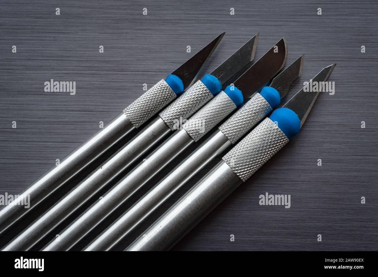 Art scalpels on brushed metal background Stock Photo Alamy