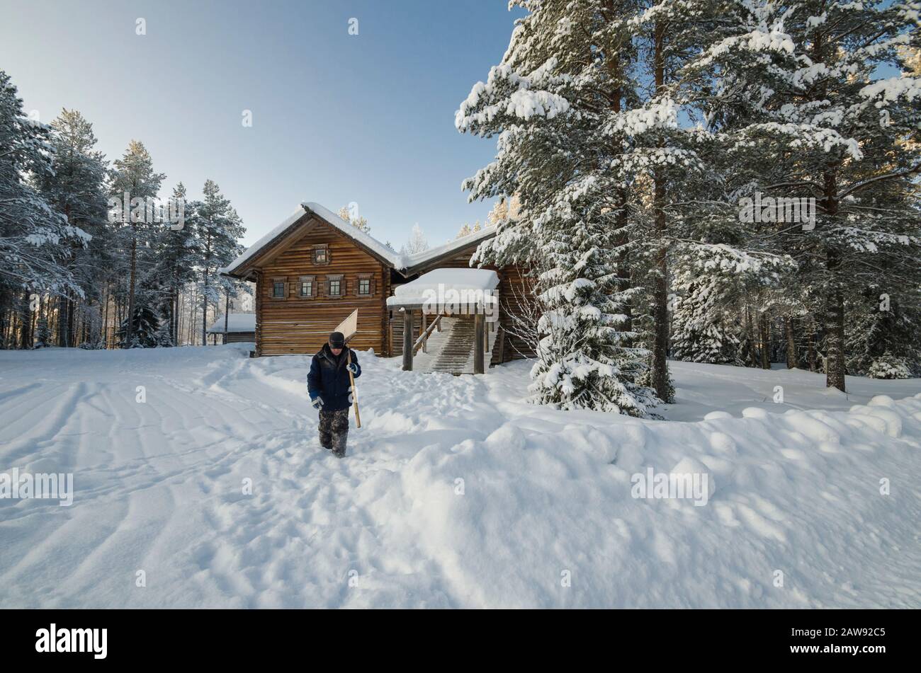 Janitor with a shovel among wooden village houses. Museum of wooden architecture 'Small Korely'. Russia, Arkhangelsk regi Stock Photo