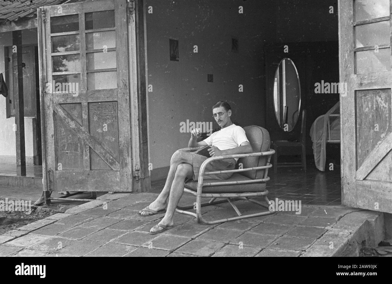 Man with glasses sitting in a rattan faureuil on the porch before the Board of side Picture. 6069 Date: 01/01/1947 Location: Indonesia Dutch East Indies Stock Photo