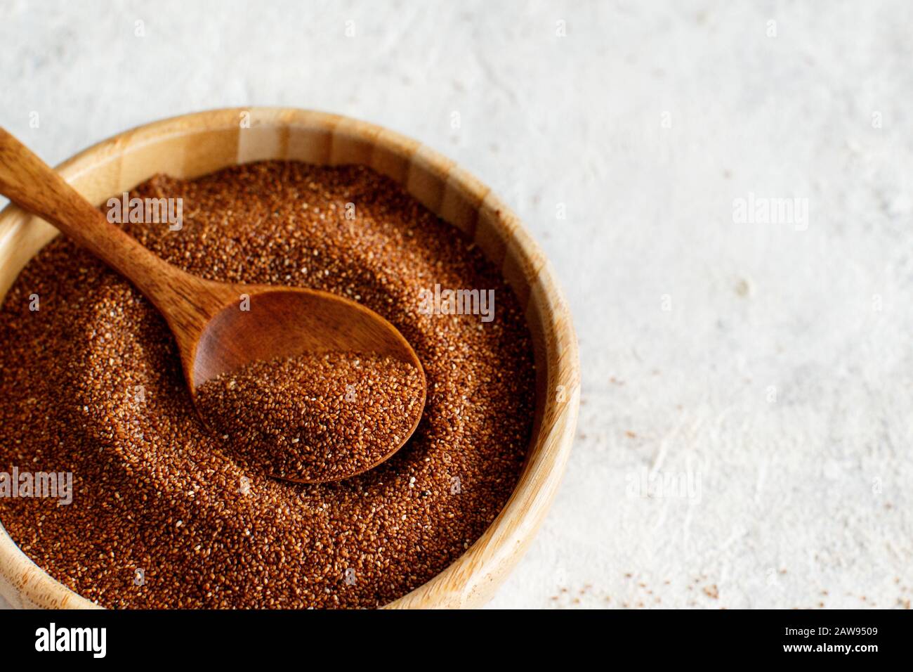 Uncooked teff grain with a wooden spoon close up Stock Photo