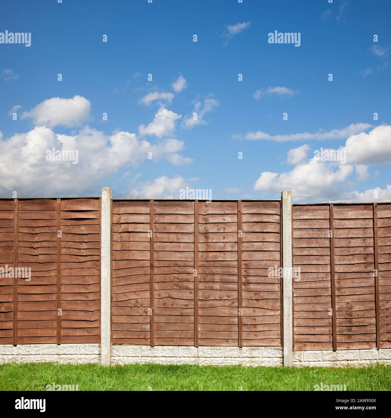 Brown wooden garden fence panels with a blue sky above Stock Photo