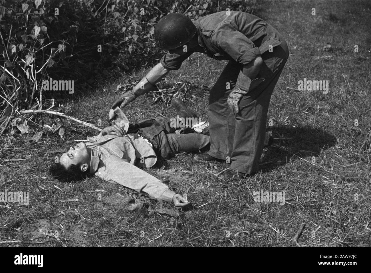 Loeboek Pakem and Baoengan  Dutch soldier bends over corpse of a Republican streider and raises his gloved hand a slip of a shirt Date: July 29 1948 Location: Indonesia, Dutch East Indies, Sumatra Stock Photo