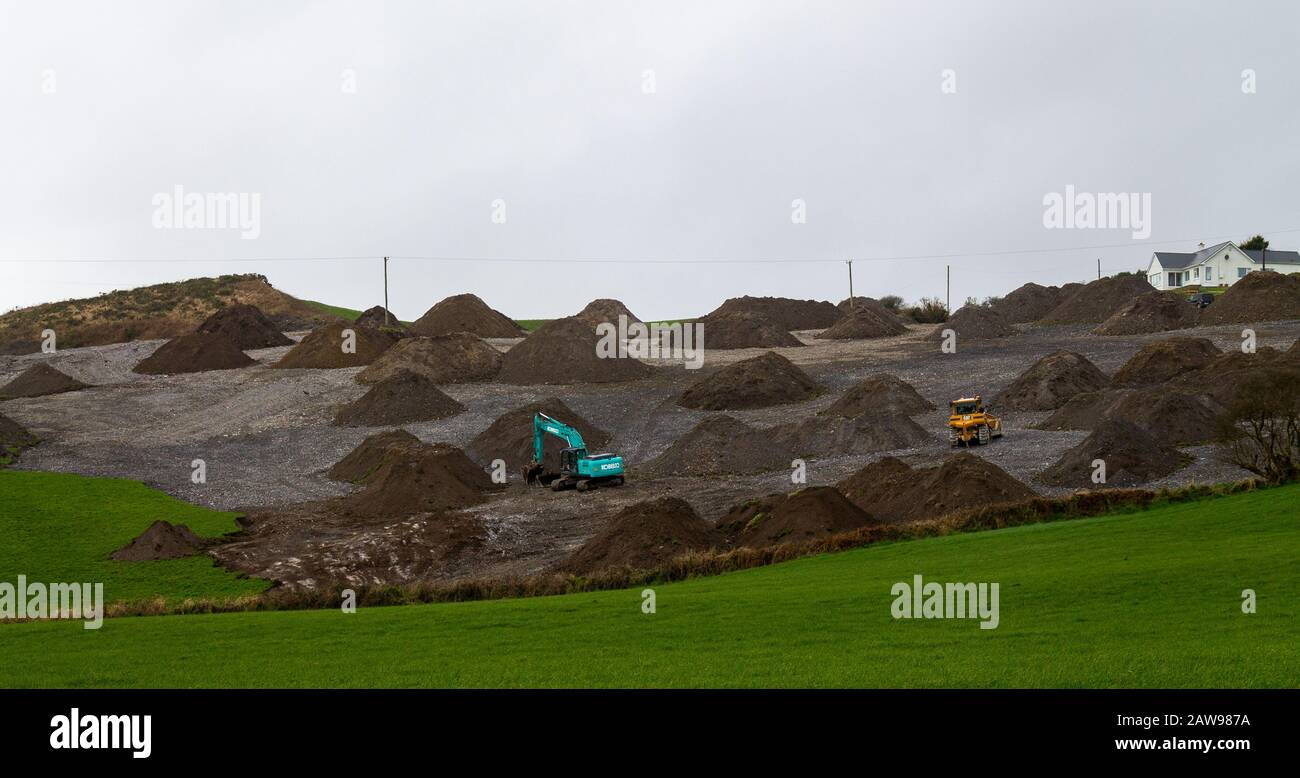 Mechanical digger clearing rocks from a field in Ireland. Stock Photo