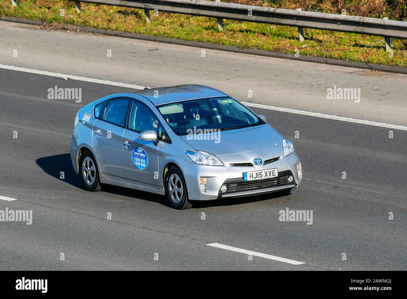 Taxi 2015 silver Toyota Prius T3 VVT-I CVT; UK Vehicular traffic, transport, modern electric vehicles, electric motor, EV, battery electric car ownership, hybrid, electric-powered performance saloon cars, on the M61 motorway highway. UK Stock Photo