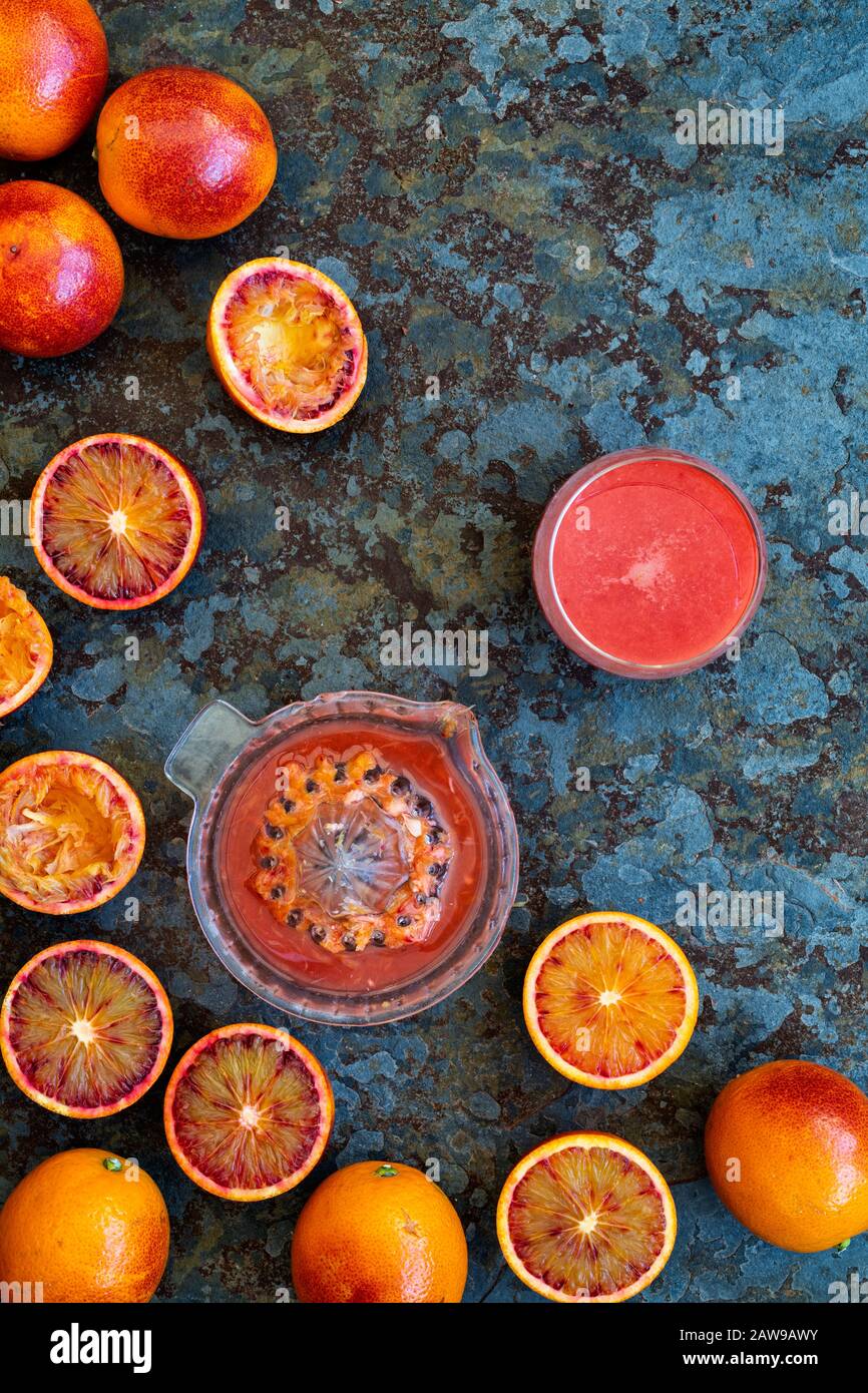 Juicing blood oranges. Blood orange juice and blood oranges on slate Stock Photo