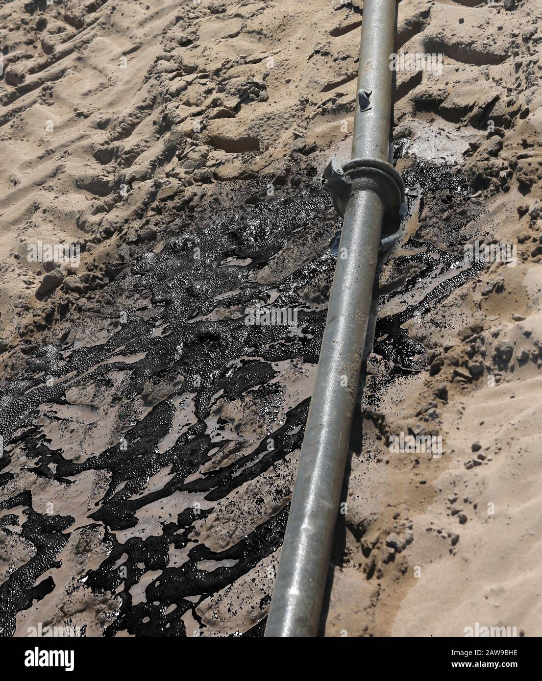 defective pipe leaks oil on the ground of a field Stock Photo